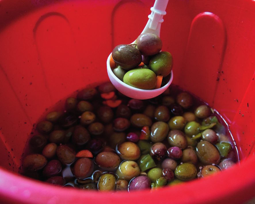 Cubo con aceitunas de distintos colores y un cazo